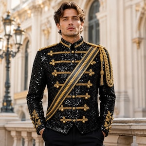 May include: A black sequined military-style jacket featuring gold braided trim, metallic buttons, and a diagonal sash. The garment includes gold shoulder epaulets with hanging tassels and intricate gold embroidery detailing on the sleeve cuffs.