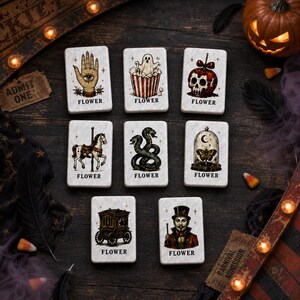 May include: Eight rectangular white tiles featuring illustrations of a palmistry hand, a ghost in popcorn, a skull apple, a carousel horse, a snake, a butterfly in a cloche, a carriage, and a ringmaster, each labeled with the word FLOWER.