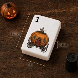 May include: A rectangular white tile featuring the number 1 and an illustration of an orange pumpkin carriage with a crown. The tile measures 1.43 inches in length, 1 inch in width, and 0.45 inches in thickness as indicated by measurement lines.