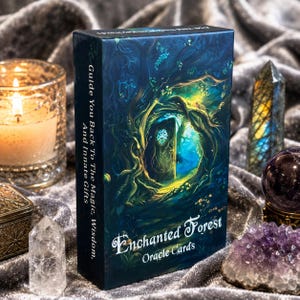 May include: A rectangular deck box for Enchanted Forest Oracle Cards featuring a dark blue forest illustration with a glowing door. The side text reads: Guide You Back To The Magic, Wisdom, And Innate Gifts. The front text reads: Enchanted Forest Oracle Cards.