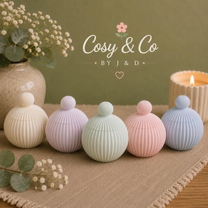 May include: Five spherical containers with ribbed textures and small round lids, arranged in a row. The containers are coloured in cream, light purple, mint green, soft pink, and light blue. The text Cosy & Co BY J & D is visible above.