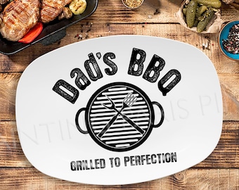 May include: White oval serving platter with black text that reads "Dad's BBQ" and a black and white illustration of a grill with crossed utensils. The text below the grill reads "Grilled to Perfection."