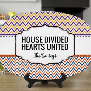 Może przedstawiać: Biała owalna tacka do serwowania z wzorem chevron w kolorze pomarańczowym, niebieskim i ż&oacute;łtym. Taca ma ozdobną ramkę z tekstem "House Divided Hearts United" i "The Canteys".