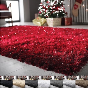 May include: A rectangular area rug featuring a deep red, shaggy pile texture with integrated shimmering metallic fibres that catch the light. The rug has a dense, long-fibre construction, providing a soft and plush appearance across its surface.