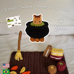 May include: A PDF pattern for a Witch's Cauldron Costume for Sylvanian and scene. Includes a crocheted black cauldron with green trim, a brown broom, a brown rectangular mat, and small crocheted food items like cookies and fruit.