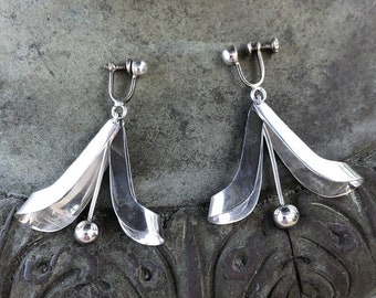 May include: A pair of silver clip-on earrings with a flower design. The earrings are made of metal and have a shiny finish.