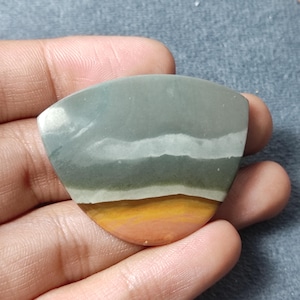 May include: A fan-shaped polished gemstone cabochon featuring horizontal bands of color. The stone displays a large section of muted sage green at the top, separated by thin white lines from a vibrant mustard yellow and terracotta orange base.