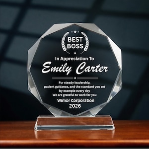 May include: A clear, faceted octagonal glass award plaque featuring white engraved text that reads: BEST BOSS, In Appreciation To Emily Carter, For steady leadership, patient guidance, and the standard you set by example every day, We are grateful to work for you, Wimor Corporation, 2026.