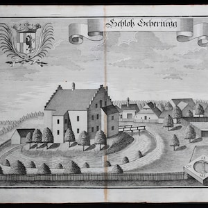 May include: A black and white engraving depicting a castle with a moat and a surrounding fence. The castle is surrounded by trees and a small village. The text "Schloß Schernegg" is displayed at the top of the image.