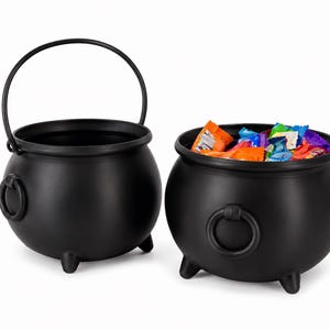 May include: Two matte black round cauldrons with three small feet and side ring handles. One cauldron has a tall arched handle and is empty, while the other is filled with various colorful individually wrapped candies in a variety of bright colors.