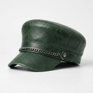 May include: A dark green military-style cap with a textured, distressed finish. The hat features a flat top, a structured brim, and a decorative silver-toned metal chain secured by a small circular stud on each side of the front band.