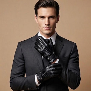 Peut inclure: Une paire de gants en cuir noir présentant un motif texturé en forme d'écailles sur le dos de la main. Les gants comprennent une petite sangle réglable au poignet avec une fermeture à bouton-pression métallique pour un ajustement sûr.