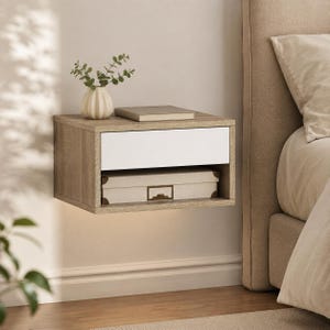 May include: A wall-mounted floating nightstand featuring a light wood grain finish and a single white drawer. The unit includes an open storage shelf below the drawer, currently holding a rectangular box with a metal handle and a small book.