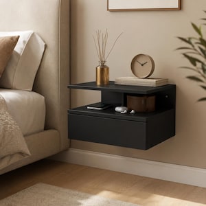Peut inclure: Une table de chevet flottante noir mat dotée d'une étagère supérieure ouverte et d'un tiroir inférieur. La surface accueille un vase en verre doré avec des brindilles séchées, une horloge ronde en bois, un smartphone, un petit récipient marron et des écouteurs blancs.