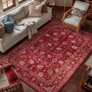 May include: A large rectangular area rug featuring a deep red background with an intricate floral and vine pattern in shades of cream, light pink, and muted blue, finished with a detailed decorative border along all four edges.