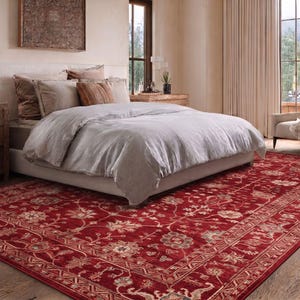 May include: A large rectangular area rug featuring a deep red background with an intricate floral pattern in shades of cream, beige, and muted green. The rug has a wide decorative border with geometric and botanical motifs throughout.