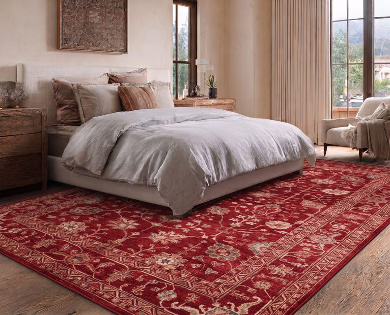 May include: A large rectangular area rug featuring a deep red background with an intricate floral pattern in shades of cream, beige, and muted green. The rug has a wide decorative border with geometric and botanical motifs throughout.