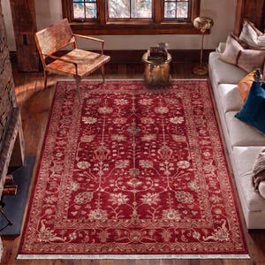 May include: A rectangular area rug featuring a deep red background with an intricate floral pattern in shades of cream, beige, and muted blue. The rug has a wide decorative border and short white fringe along the top and bottom edges.