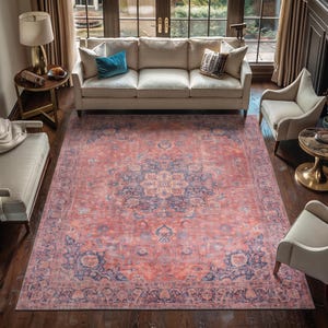 May include: A large rectangular area rug featuring a faded coral and dusty blue color palette. The design includes a central floral medallion surrounded by intricate botanical patterns and a wide decorative border in matching muted tones.