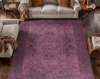 May include: A large rectangular area rug featuring a deep magenta and dark purple color palette with a distressed, intricate floral pattern and a wide decorative border, centered on a dark hardwood floor in a living room setting.