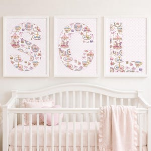 May include: Three framed wall art prints featuring the letters S, C, and L. Each letter is filled with a repeating pattern of pink and pastel-colored illustrations including carousels, hot air balloons, tea sets, and bows on a white polka dot background.