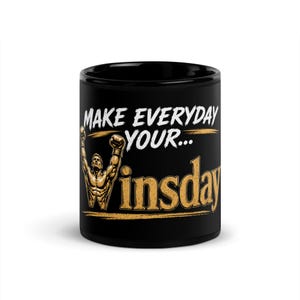 Peut inclure: Un mug en céramique noire orné d'un graphique représentant une silhouette musclée les bras levés en signe de victoire. Le texte indique "MAKE EVERYDAY YOUR..." en blanc et "insday" en doré, le "W" étant formé par le corps et les bras.