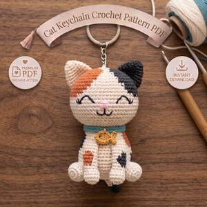 May include: A crochet cat keychain with a calico pattern of cream, orange, and dark gray yarn. The cat has a teal collar with a small gold fish charm, embroidered closed eyes, and a pink nose. Text reads Cat Keychain Crochet Pattern PDF.