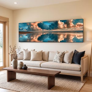 Peut inclure: Une impression d'art mural panoramique représentant un ciel spectaculaire avec des nuages bleu profond et pêche se reflétant sur une étendue d'eau calme. La peinture de paysage horizontale affiche une ligne d'horizon sereine sur un mur clair.