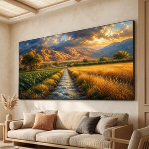 May include: A rectangular wall art print featuring a landscape scene with a central stream flowing through a golden wheat field and green crops. In the background, rugged mountains are illuminated by a warm, glowing sunset sky with clouds.