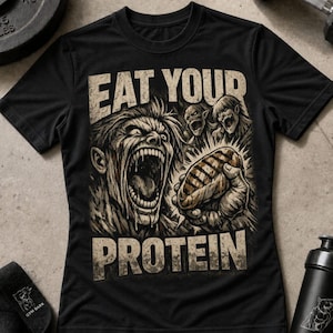 Könnte beinhalten: Ein schwarzes Kurzarm-T-Shirt mit einem Grafikdruck einer schreienden humanoiden Figur, die ein Stück Fleisch hält. Der Text EAT YOUR PROTEIN ist in einer abgenutzten beigen Schrift über und unter der zentralen Illustration gedruckt.
