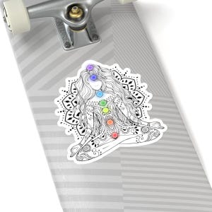 May include: A black and white illustration of a woman sitting in a yoga pose with a mandala behind her. The woman has seven chakras represented by colored circles along her body.