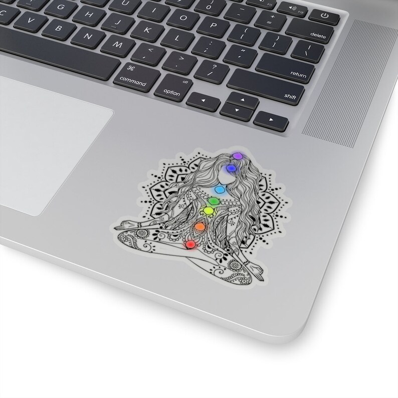 May include: A black and white illustration of a woman sitting in a lotus position with a mandala behind her. The woman has seven chakras represented by colored circles on her body.