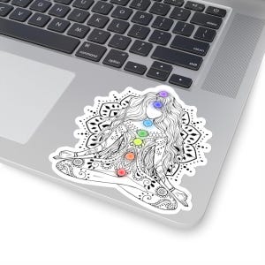 May include: Black and white line art illustration of a woman in a yoga pose with a mandala behind her. The woman has seven colorful chakras, representing the seven energy centers of the body.