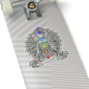 May include: A black and white illustration of a woman meditating with a mandala behind her. The woman has seven chakras represented by colored circles along her spine.