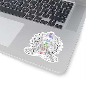 May include: A black and white line drawing of a woman in a yoga pose with seven colorful chakras. The woman is surrounded by a mandala design.