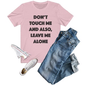 May include: Pink t-shirt with the text "Don't touch me and also, leave me alone" in black.