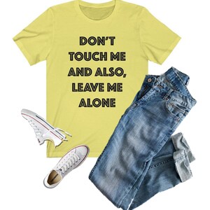 May include: A yellow t-shirt with the text "DON'T TOUCH ME AND ALSO, LEAVE ME ALONE" printed in black.