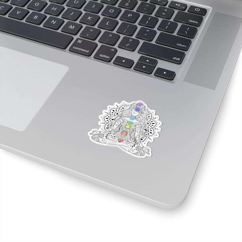 May include: A black and white illustration of a woman meditating with a mandala behind her. The woman has seven chakras represented by colored circles on her body.
