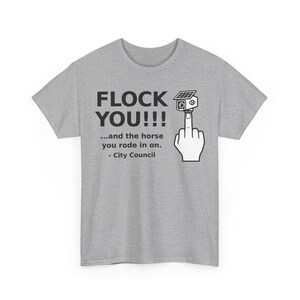 May include: A heather gray t-shirt featuring black text that reads FLOCK YOU!!! ...and the horse you rode in on. - City Council. Next to the text is a graphic of a hand making an obscene gesture with a security camera mounted on the middle finger.