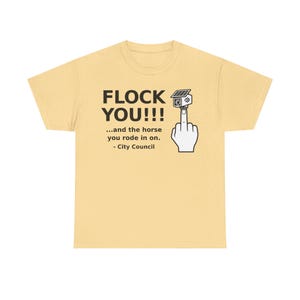 May include: A light yellow t-shirt featuring black text that reads FLOCK YOU!!! ...and the horse you rode in on. - City Council. Next to the text is a graphic of a hand making an obscene gesture with a security camera mounted on the fingertip.