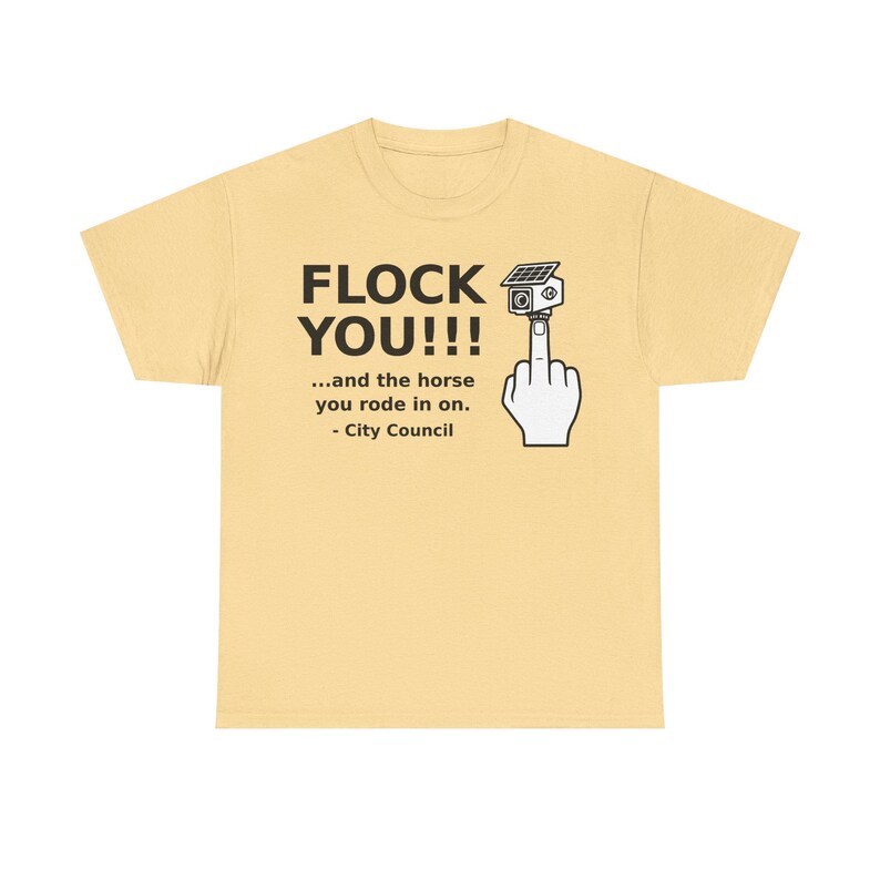 May include: A light yellow t-shirt featuring black text that reads FLOCK YOU!!! ...and the horse you rode in on. - City Council. Next to the text is a graphic of a hand making an obscene gesture with a security camera mounted on the fingertip.