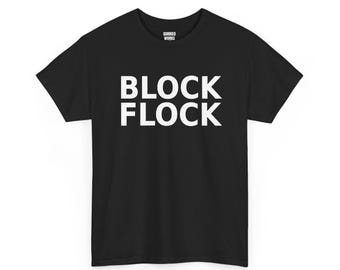 May include: A black short-sleeved t-shirt featuring the white text BLOCK FLOCK printed in a bold, sans-serif font across the chest. The inner neck label displays the white text QUIRKED WORKS on a black background.