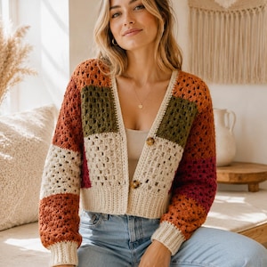 May include: A long-sleeve crochet cardigan featuring a patchwork granny square pattern in shades of rust orange, olive green, cream, and burgundy. The garment has a V-neckline, a ribbed hem, ribbed cuffs, and two brown tortoiseshell-style buttons.