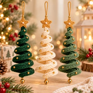 Könnte beinhalten: Drei spiralförmige Weihnachtsbaumschmuckstücke aus gehäkeltem Garn. Zwei Bäume sind dunkelgrün und einer ist cremefarben. Jeder Baum ist mit einem gehäkelten Stern mit einer kleinen weißen Perle und einer goldenen Glocke an der Basis versehen.