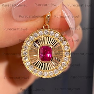 May include: A circular gold pendant featuring a central cushion-cut vibrant pink gemstone surrounded by a sunburst-style textured gold frame and an outer border of small round white diamonds, finished with a gold bail at the top.
