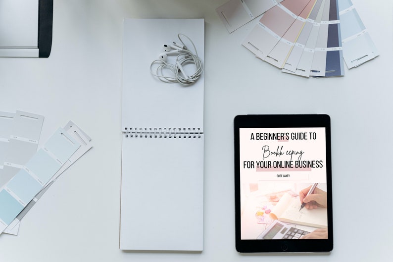 May include: A tablet displaying an ebook cover titled "A Beginner's Guide to Bookkeeping for Your Online Business" by Elise Landry. The cover features a hand writing in a notebook with a calculator nearby.