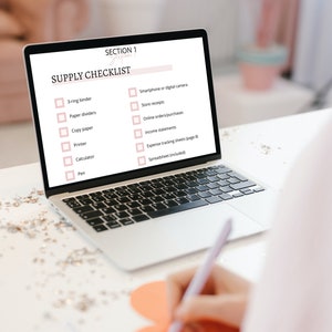 May include: A laptop computer screen displays a checklist titled "Supply Checklist" with a list of items needed for a business, including a 3-ring binder, paper dividers, copy paper, a printer, a calculator, a pen, a smartphone or digital camera, store receipts, online orders/purchases, income statements, expense tracking sheets, and a spreadsheet.