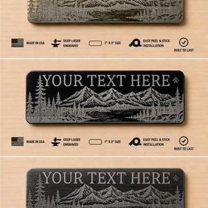 May include: Three rectangular metal plates measuring 1 inch by 3 inches, featuring a laser-engraved mountain and forest landscape. The plates come in brass, black, and dark gray finishes, each with the text YOUR TEXT HERE and an arrow icon.