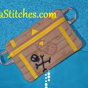 Pode incluir: Bolsa marrom com zíper com tema pirata, com caveira e ossos cruzados, um design de baú do tesouro e o texto "LunaStitches.com". A bolsa tem detalhes amarelos e uma alça cinza.