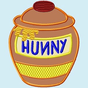 Può includere: Un barattolo di miele marrone con un coperchio rosso e un motivo a nido d'ape giallo. La parola "HUNNY" è scritta in lettere blu sulla parte anteriore del barattolo.